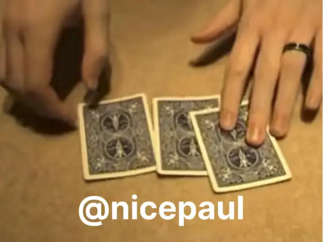 Hands performing a card trick with three playing cards